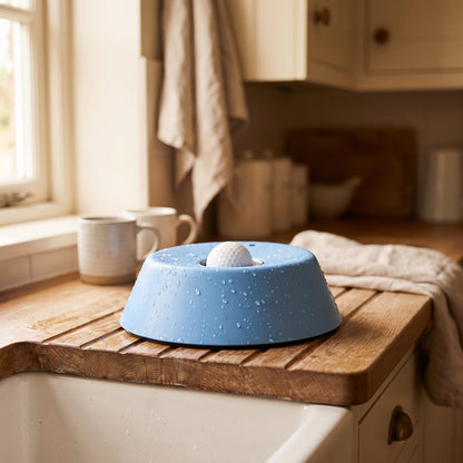 The bowl freshly rinsed on a wooden draining board beside a kitchen sink