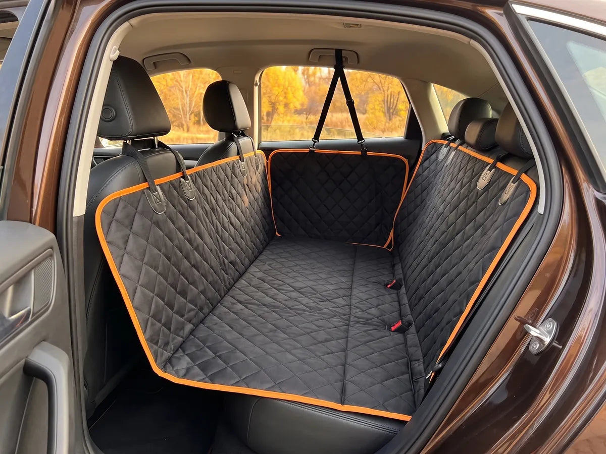 A black quilted car seat cover with orange trim fitted neatly across an empty clean back seat